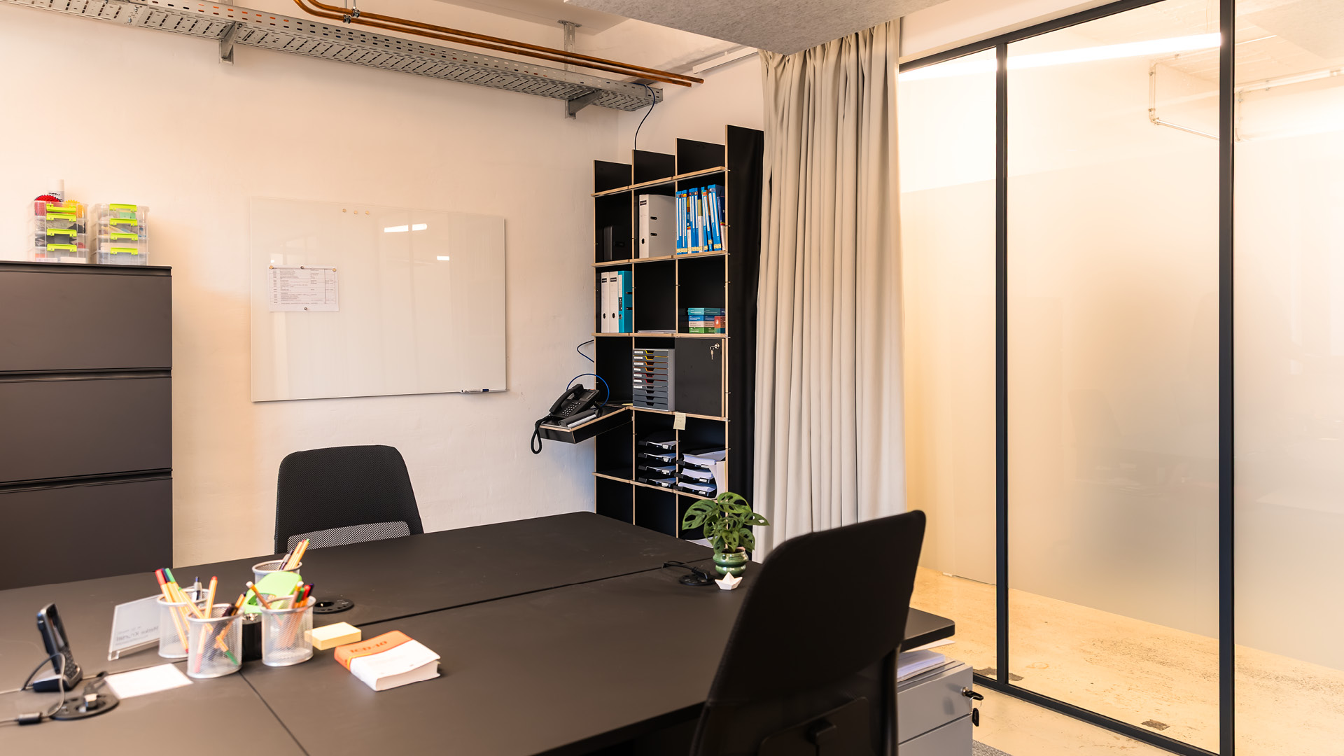 Büroarbeitsplatz der APV Münster mit Glasabtrennung, Vorhanglösung und flexiblen Arbeitsbereichen für konzentrierte Arbeit und vertrauliche Gespräche.