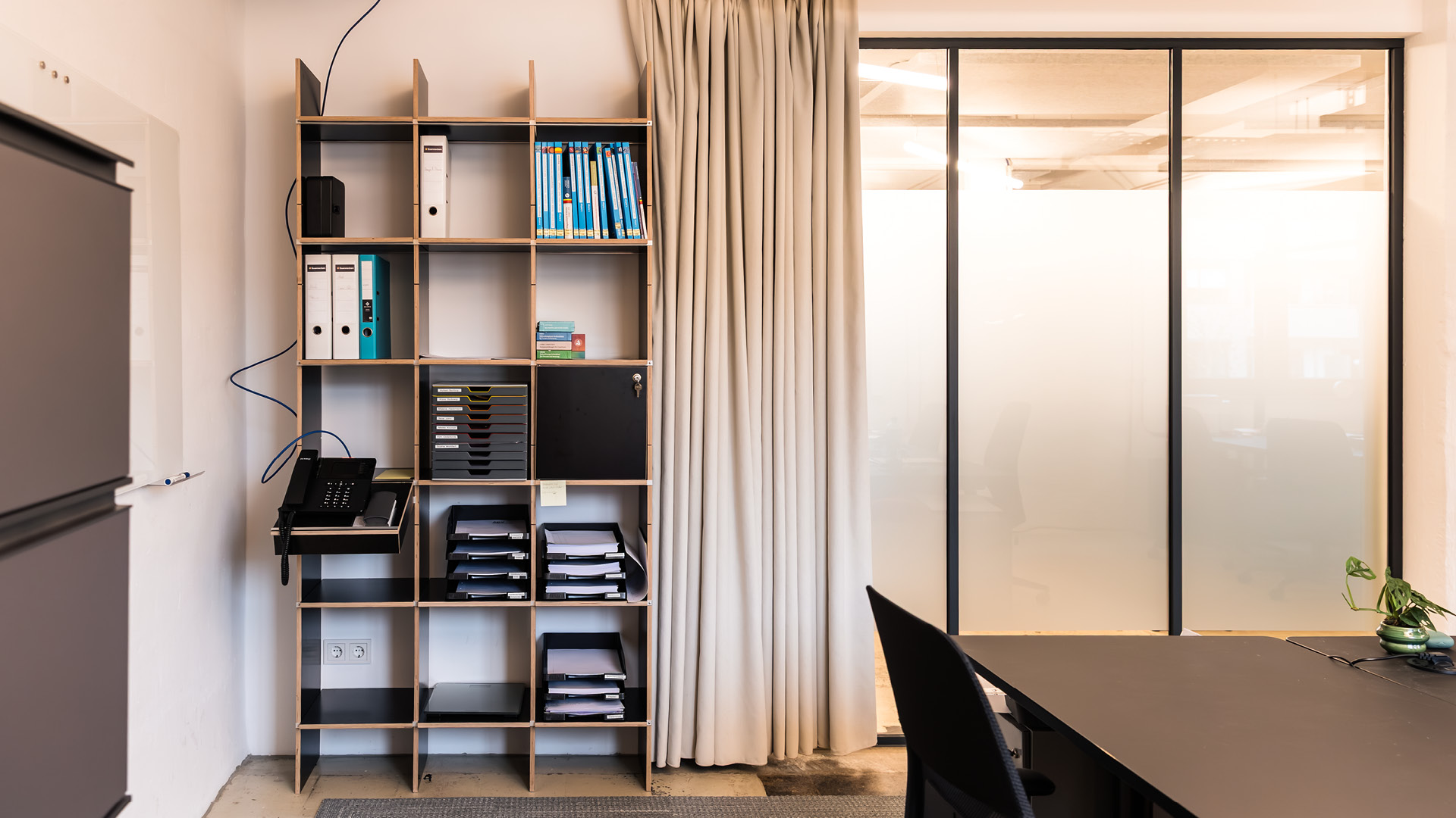 Arbeits- und Besprechungsbereich der APV Münster mit flexibler Abschirmung durch Vorhänge und transluzente Glaswände.