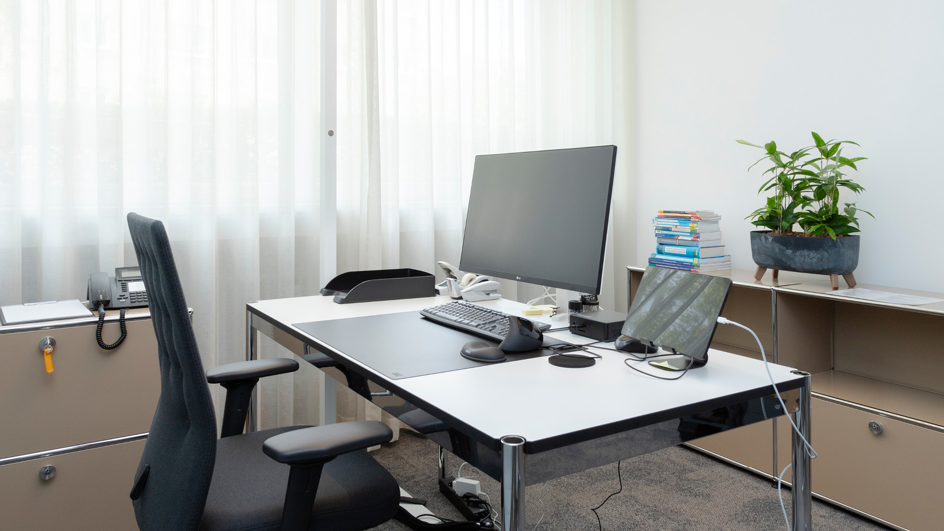 Arbeitsplatz im CIP Erlangen mit höhenverstellbarem Schreibtisch und USM Haller Stauraummöbeln.