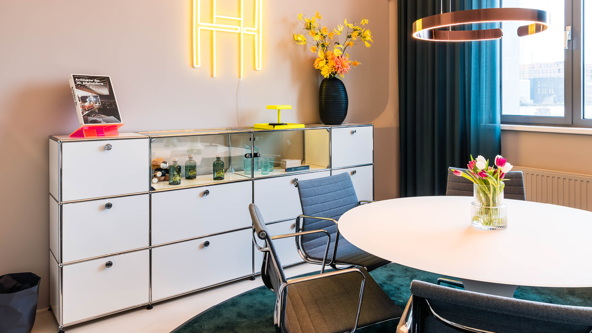 USM Haller Sideboard im Besprechungsbereich des Referenzprojekts Heimathafen Immobilien in Münster, kombiniert mit rundem Tisch, Designbeleuchtung und wohnlicher Bürogestaltung für kommunikative Meetings.