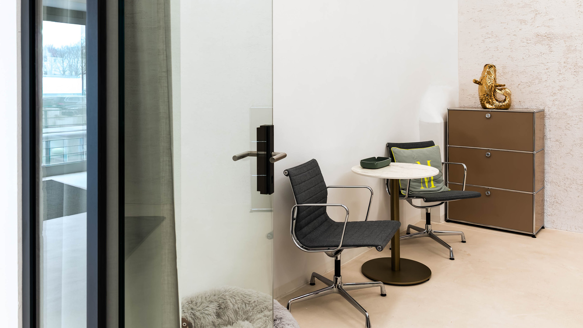 Kleine Besprechungsecke mit USM Haller Sideboard im Referenzprojekt Heimathafen Immobilien in Münster, mit Glastrennwand, Sitzgruppe und klar zoniertem Rückzugsbereich für kurze Abstimmungen.