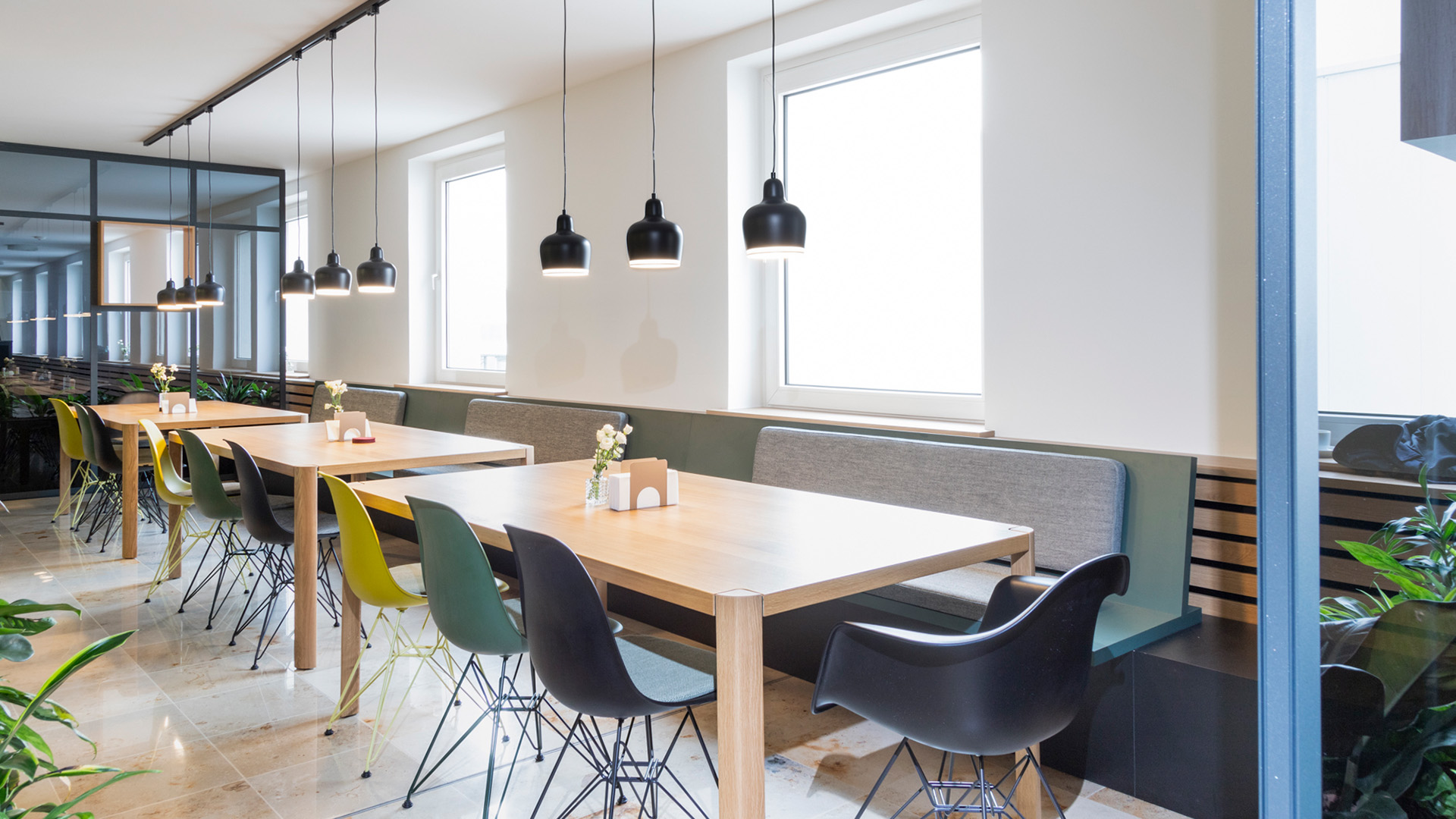 Ein Restaurant mit Tischen und Stühlen, das von projekt k in Münster als Referenzprojekt gestaltet wurde, sowie eine Lounge-Einrichtung bei der RATIO Unternehmensgruppe.