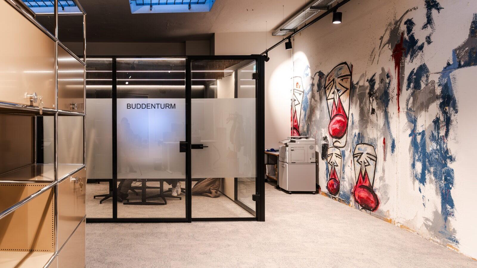Graffiti an der Wand und Besprechungsboxen mit Glas- und Schwarzmetall-Elementen für diskrete Gespräche in der Pop-Up-Filiale.